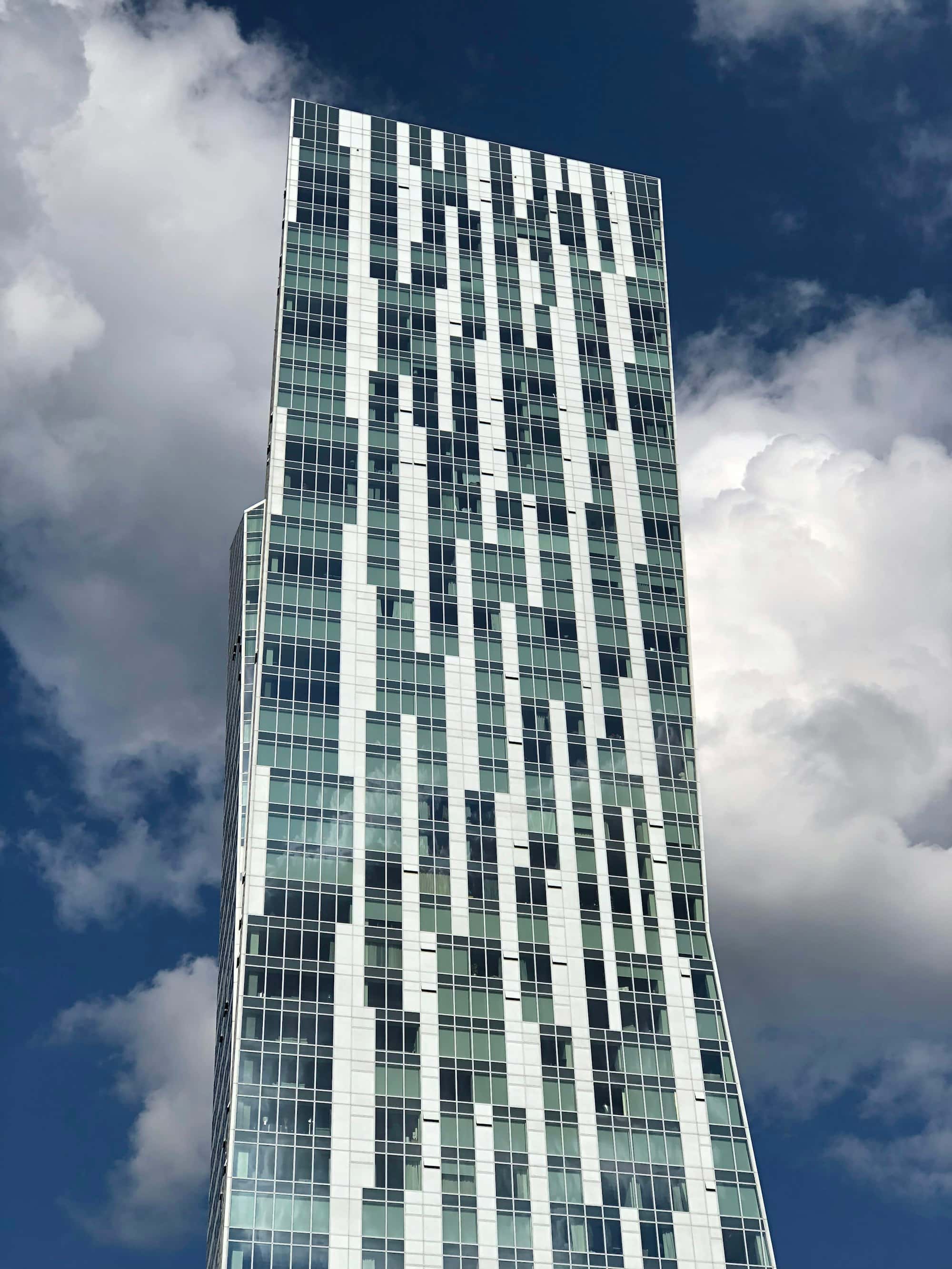 Tall curved glass tower with a dense window grid, seen from below