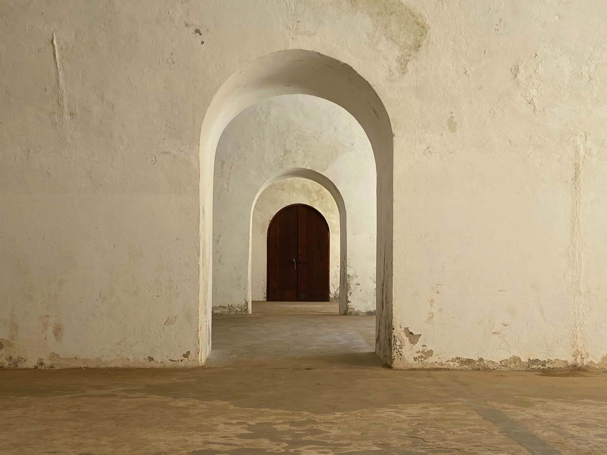 Whitewashed stone archways receding toward a dark wooden door